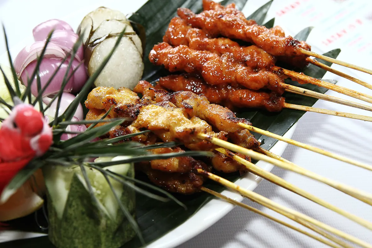 Chicken and meat satay skewers with rice cakes and vegetables